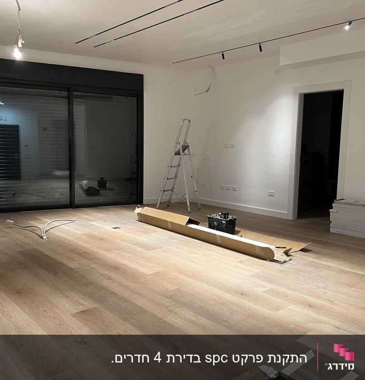 רצפת פרקט מותקנת בחדר עם סולם וקרטון